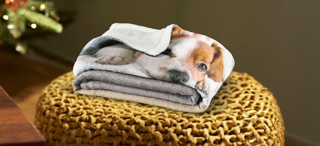A folded towel with a cute dog motif on a cozy armchair