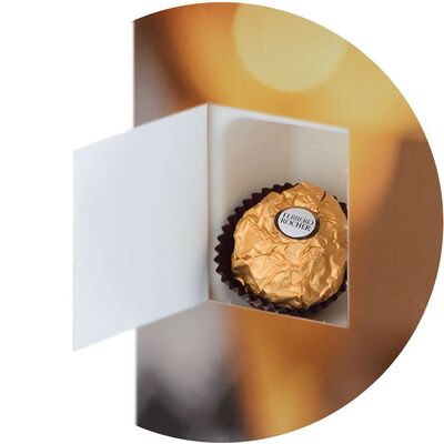 A golden praline in an open box with a colorful background