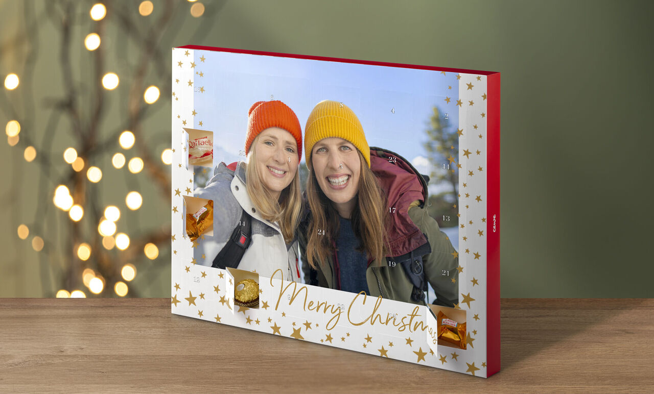 A Christmas calendar with festive design and photos of two friends outdoors, smiling in colorful beanies.