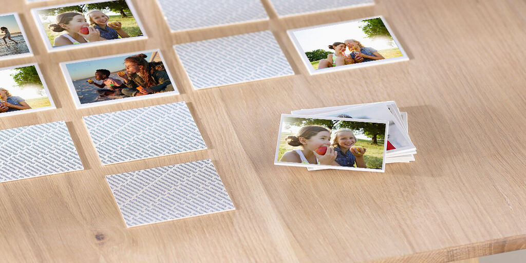 Two children enjoy an ice cream outdoors. On a table are snapshots arranged creatively.