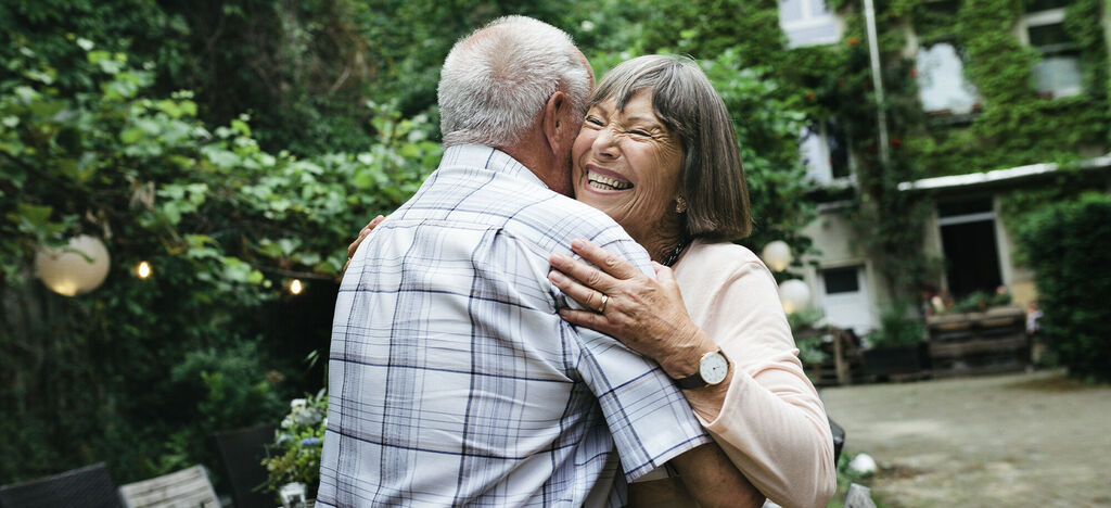 A happy couple embraces lovingly outdoors, surrounded by green nature. A heartwarming snapshot radiating joy.
