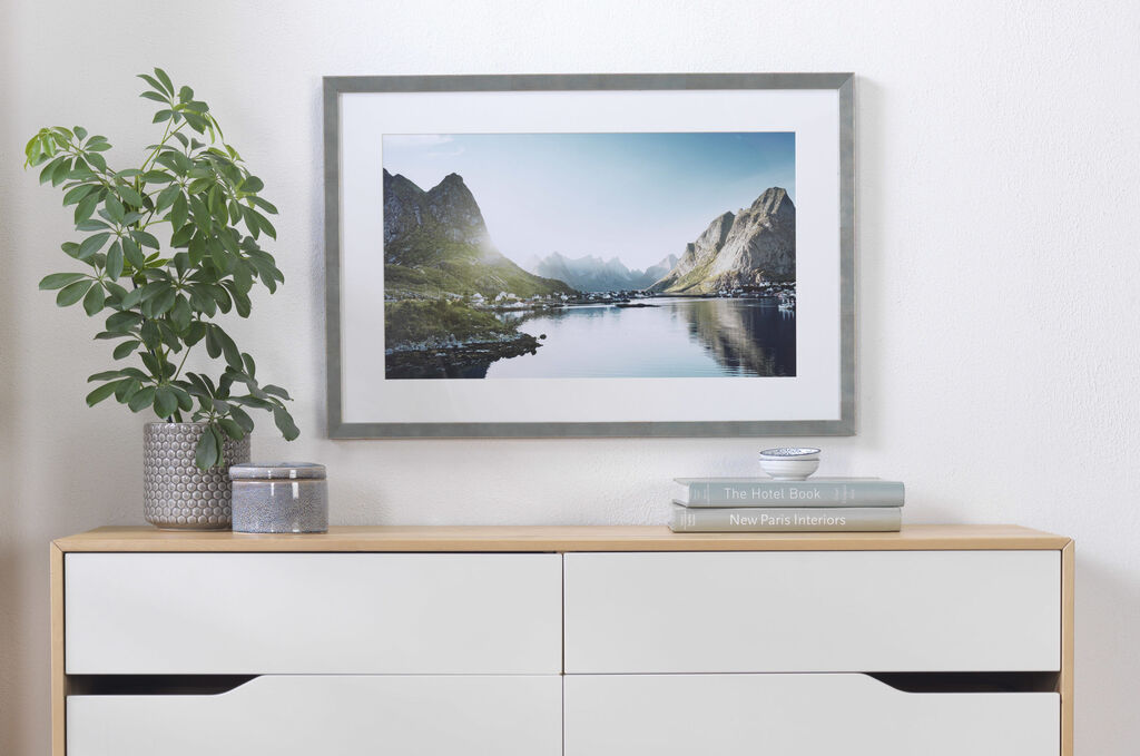 A stunning landscape image of mountains at a tranquil lake, framed in an elegant wooden frame.