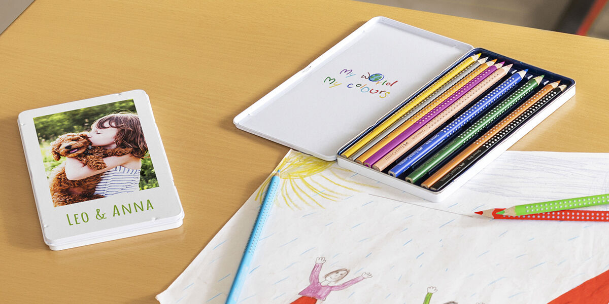 A colorful set of colored pencils next to a creative book featuring a photo of a girl and her dog on the cover.