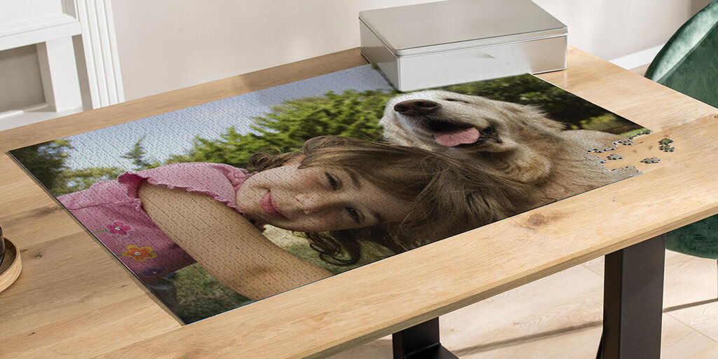 A happy girl relaxes with a dog on a wooden board. She has long hair and wears a pink shirt with flowers. Her face shows joy and affection for the dog.