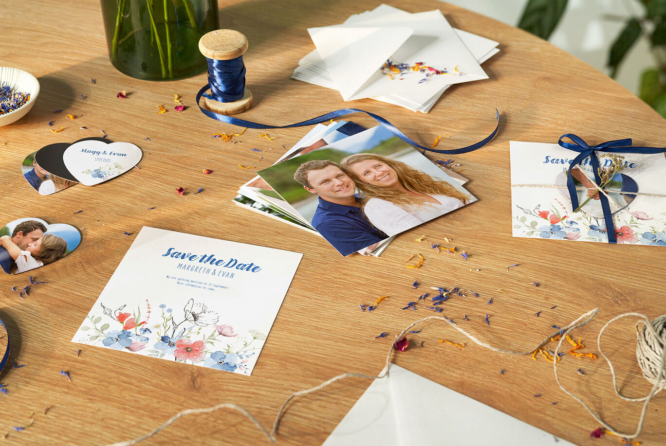 A lovingly designed table with Save the Date cards, photos of a couple, and colorful flowers. Perfect for special occasions.