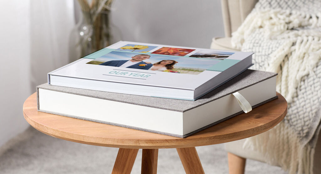 Two CEWE photo books on a wooden table.